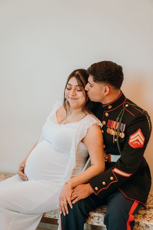 A couple in formal attire poses together, with one person wearing a military dress uniform and the other in white.