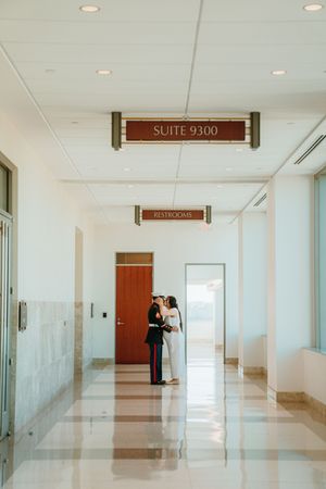 Modern office hallway with glass walls, recessed lighting, and a brown door marked Suite 9300 at the end.