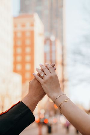 Two hands clasped together in a high five gesture against an urban backdrop with orange buildings in soft focus.