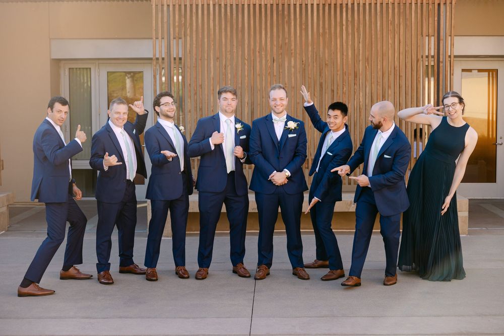A creative wedding party photo showing only the legs and shoes of people lined up against a wooden wall.
