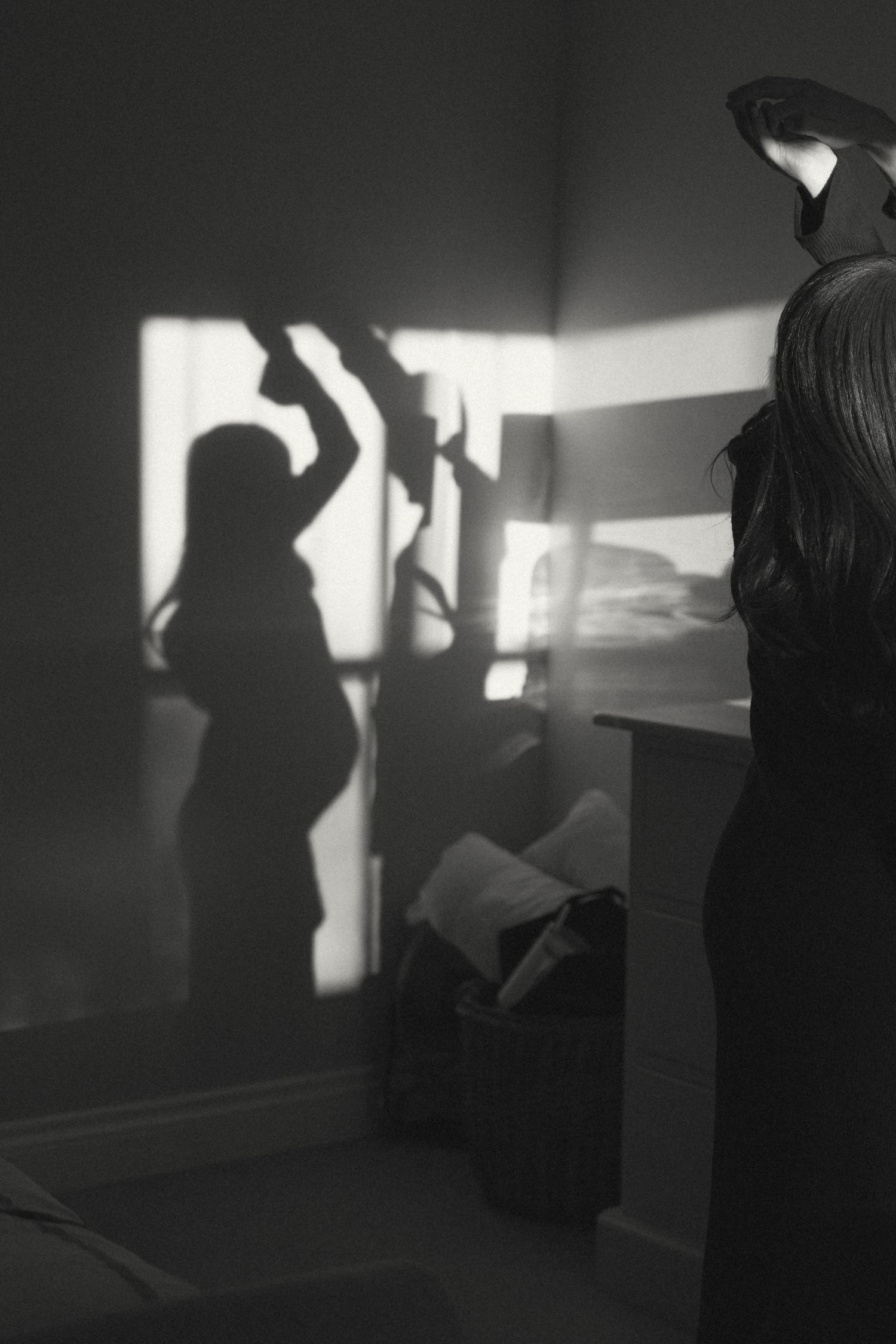 Dramatic black and white image capturing dark silhouettes against bright windows in an interior space.