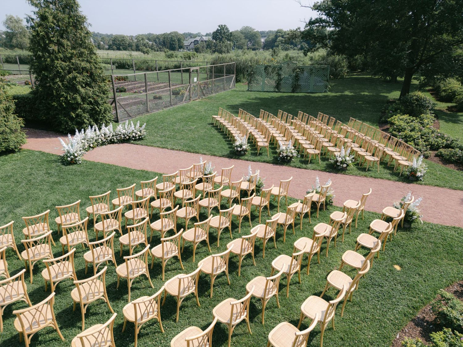 Rows of wooden folding chairs set up on a lush green lawn for an outdoor wedding ceremony. - Elawa Farm