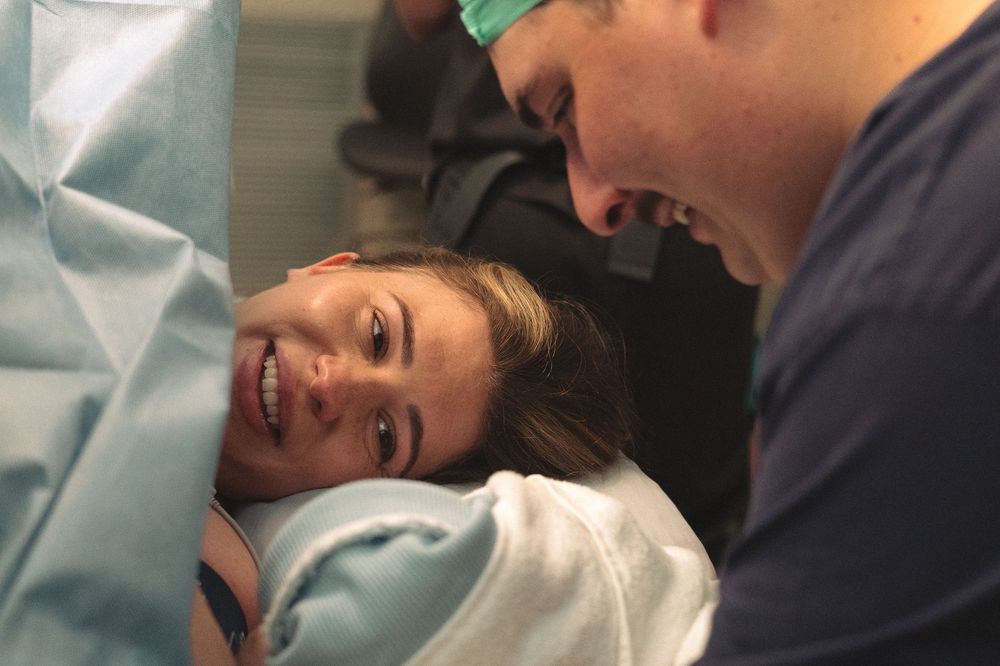 Medical staff attending to a patient during childbirth in a hospital delivery room.