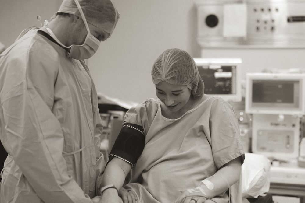 A healthcare worker takes a blood pressure reading from a patient in a hospital operating room setting.