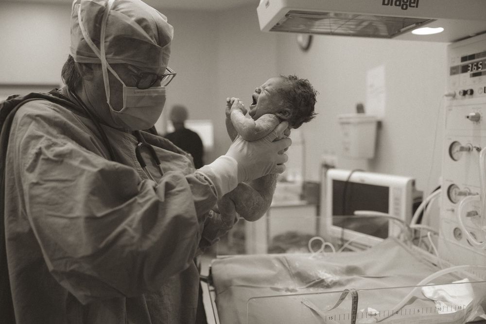 Medical professionals in protective gear work together in a hospital emergency room setting.