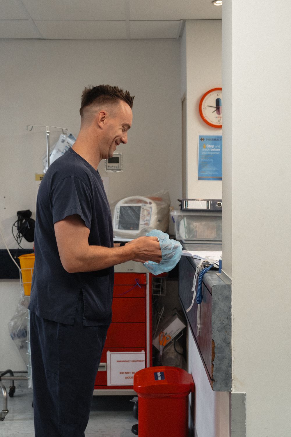 Person in dark shirt interacting with a red postal box or machine in a white interior space.