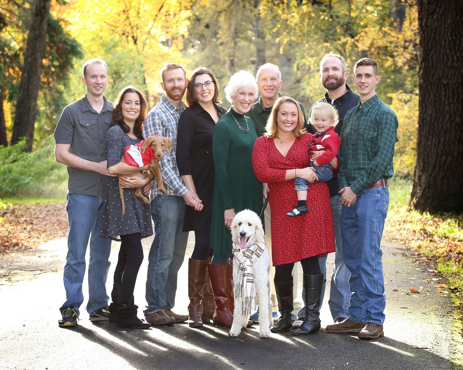 A group of people standing together outdoors in autumn with golden foliage in the background.