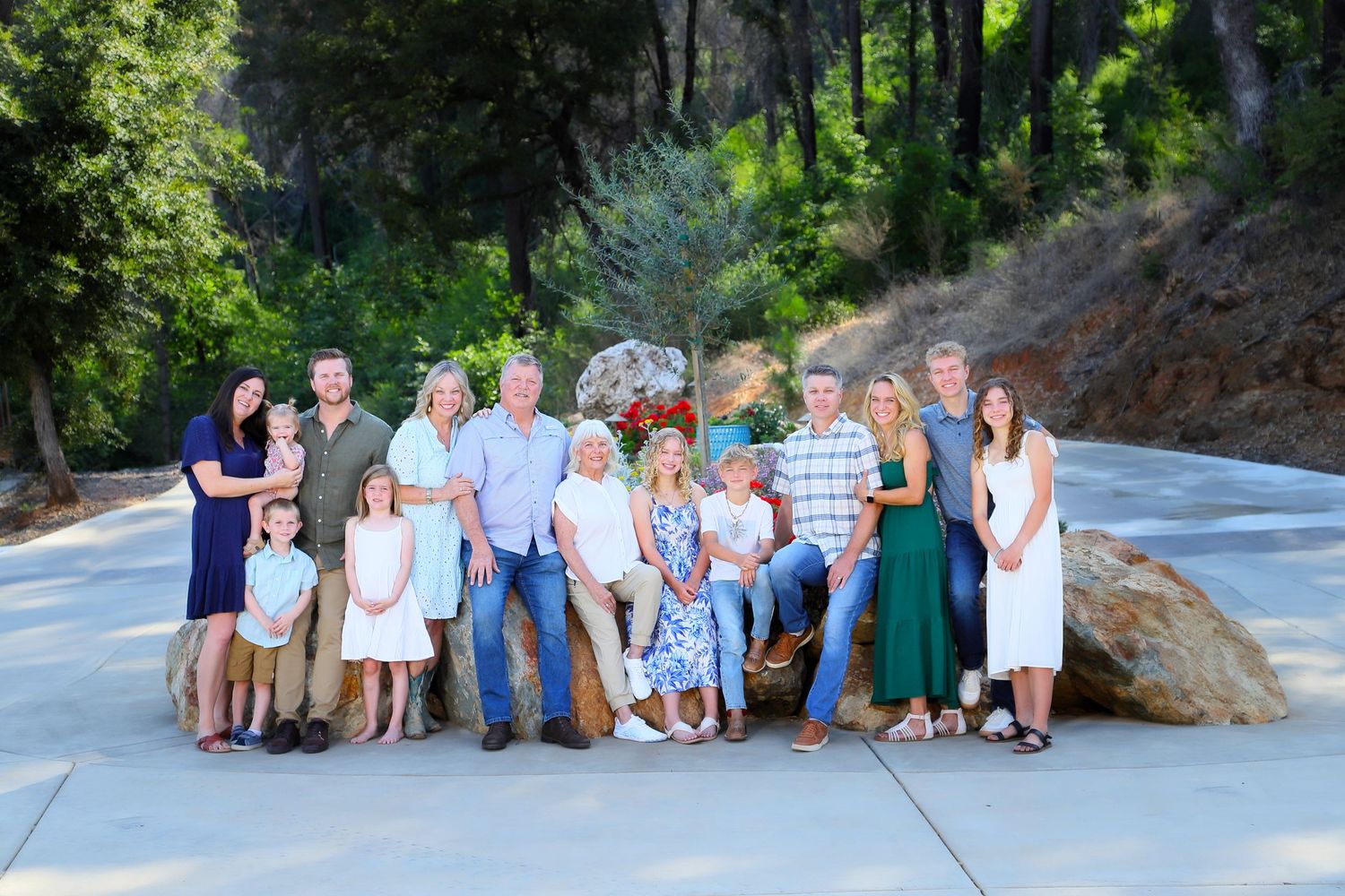 Large family group in coordinated white and blue outfits poses together on outdoor stone steps.