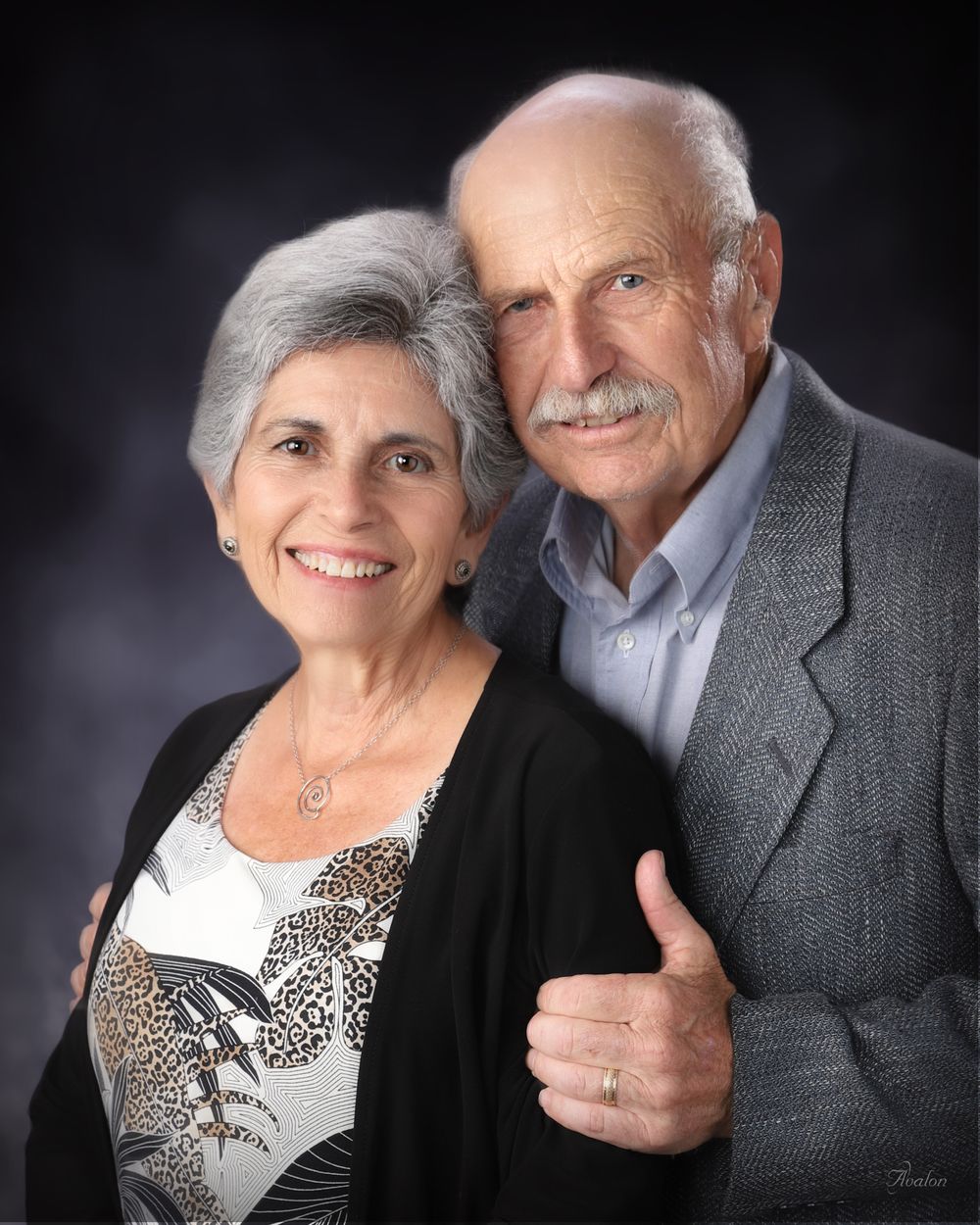 Senior couple poses together in formal attire against dark background in series of romantic portrait shots.