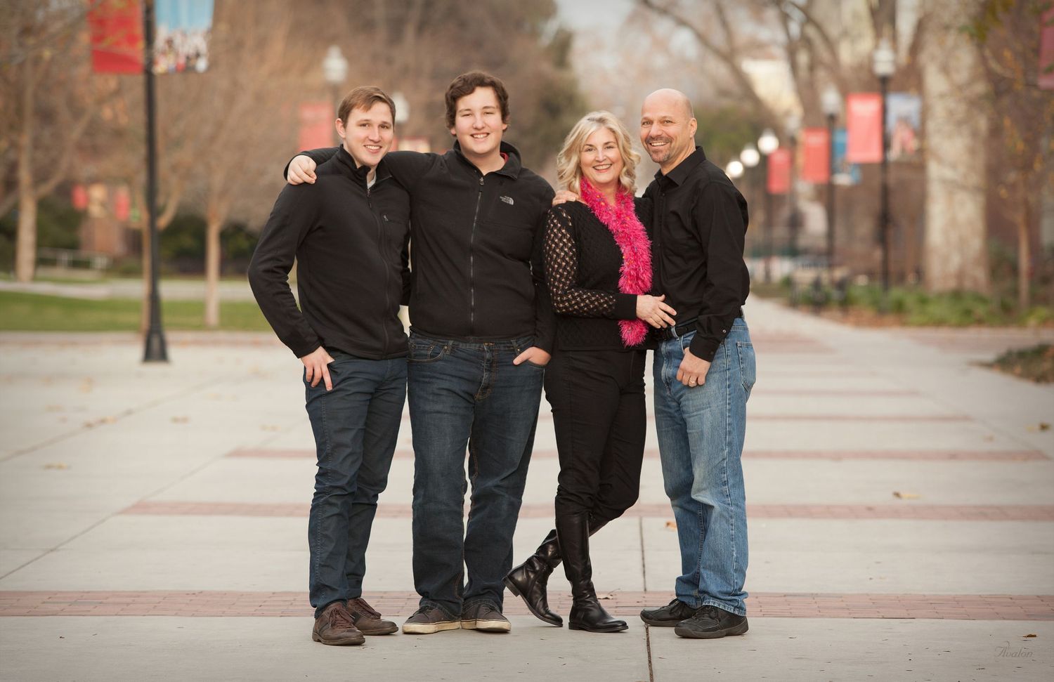 A group of people in casual clothing pose together outdoors on a brick pathway during autumn.