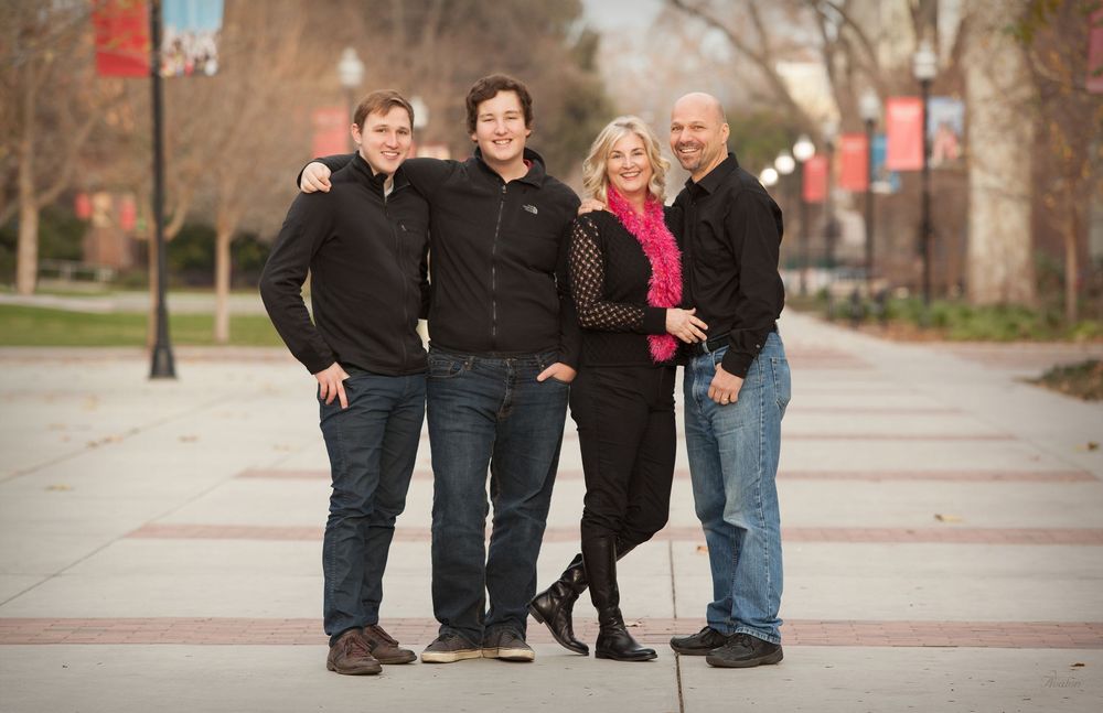 A group of people in casual clothing pose together outdoors on a brick pathway during autumn.
