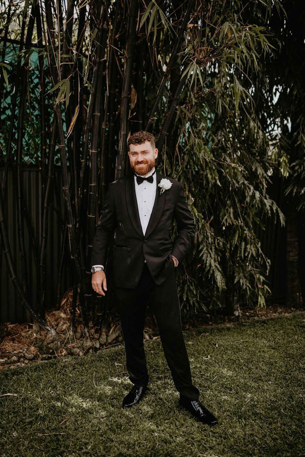 Formal wedding attire against natural bamboo garden backdrop.