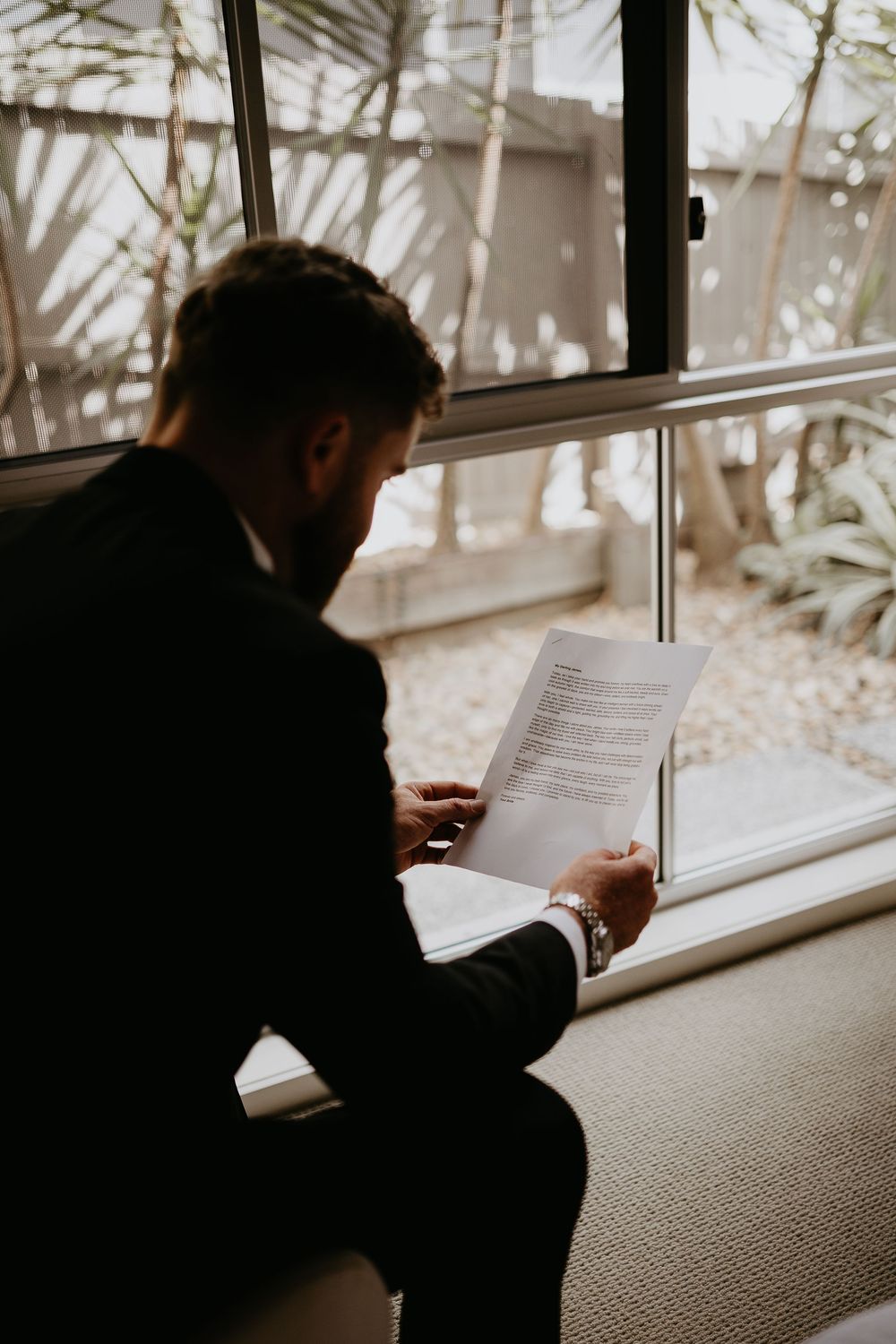 Silhouette of person reading documents by a window in natural light.