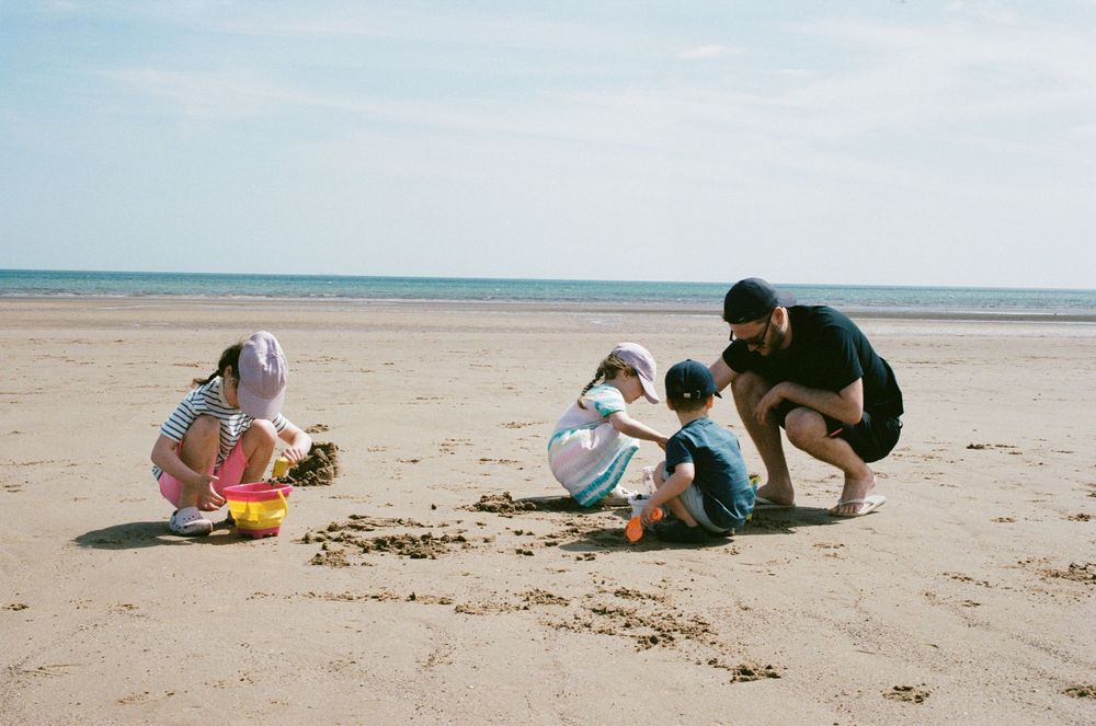 People digging and playing in the sand at a sunny beach while enjoying outdoor activities and recreation.