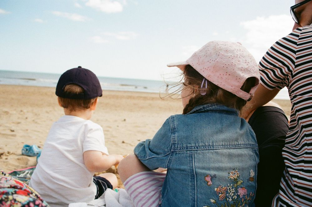 People enjoying a sunny day at the beach with sun hats and casual summer attire.