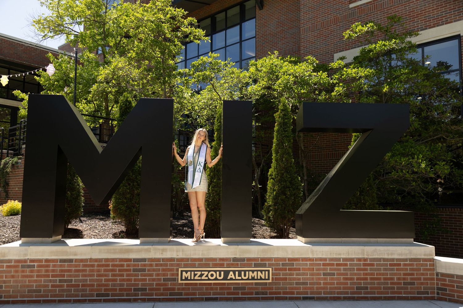 A woman in a white top and black skirt poses gracefully against the arch at Memorial Student Union.