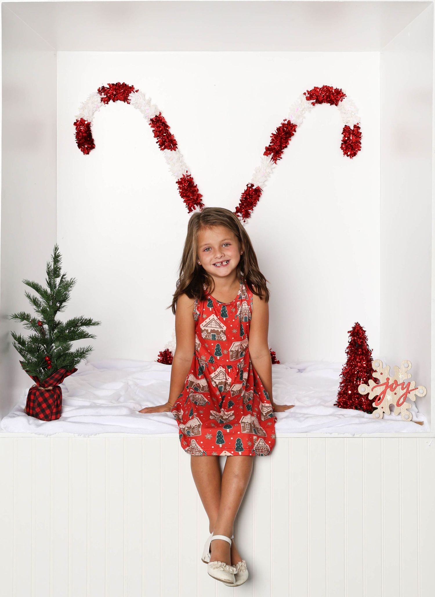 Red floral dress photo against white backdrop with festive tinsel decorations. Box photography session