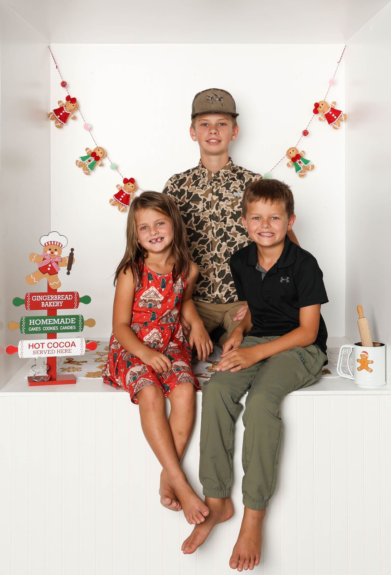 Family group sitting together in casual outfits against white background with holiday decor. Box photography session
