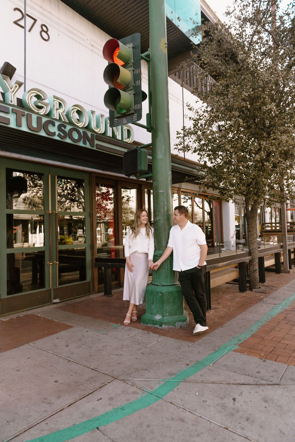 A couple stands outside a storefront with a traffic light and green line painted on the sidewalk in Tucson.