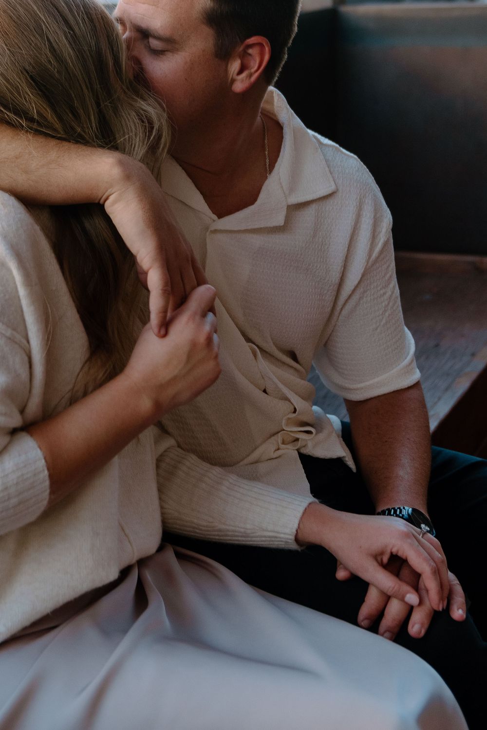 An intimate moment captured between a couple in light colored clothing sitting close together.