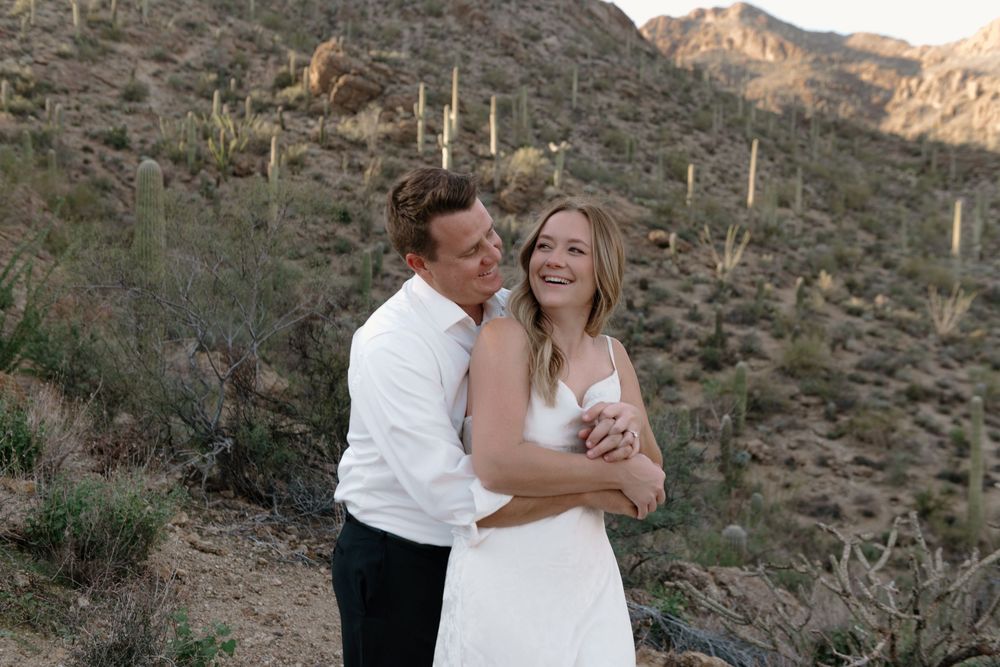 A couple shares romantic moments against a scenic desert mountain backdrop during golden hour.