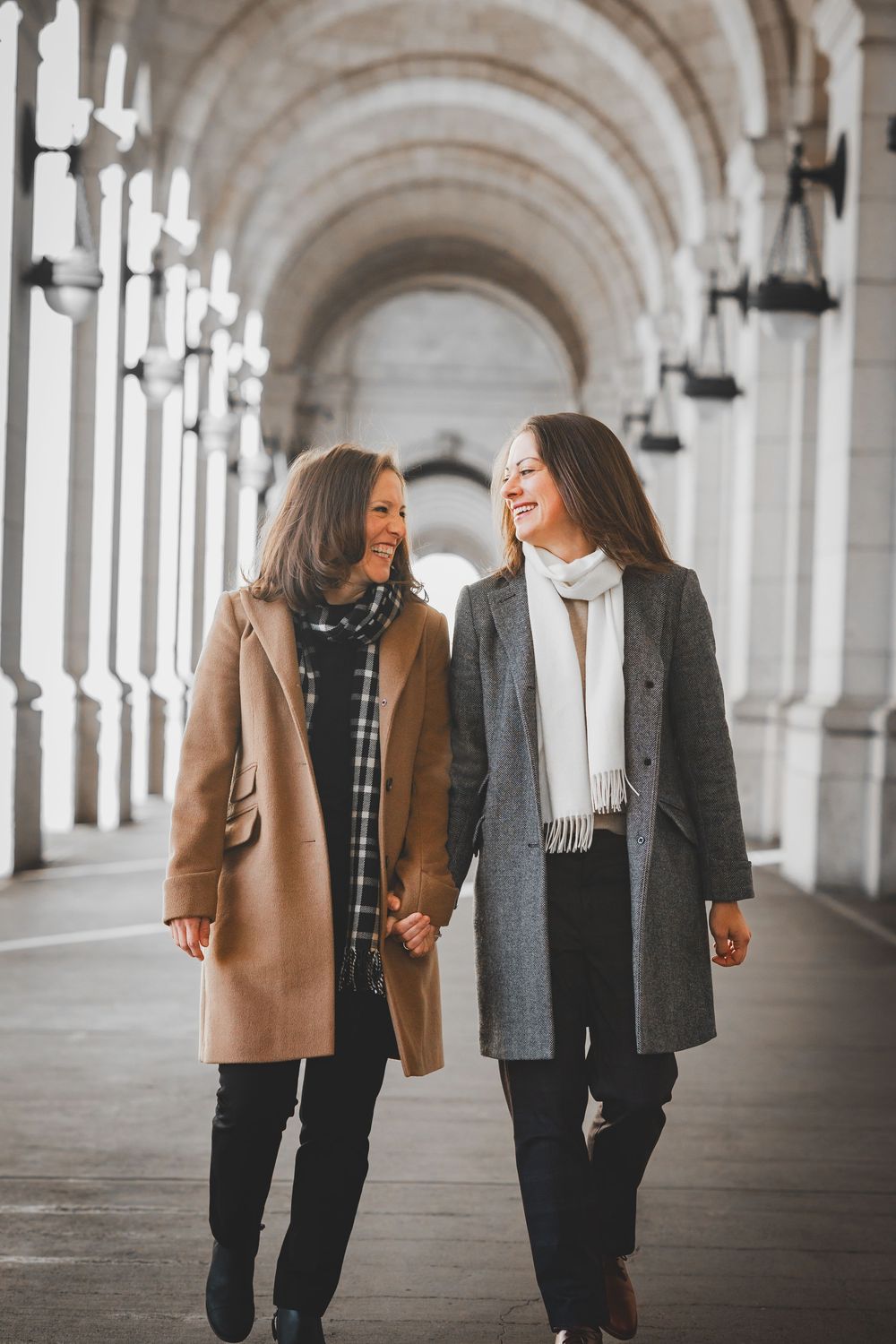 A couple walking and laughing together in the arched hallway of Union Station, one of the best winter spots for proposals in DC