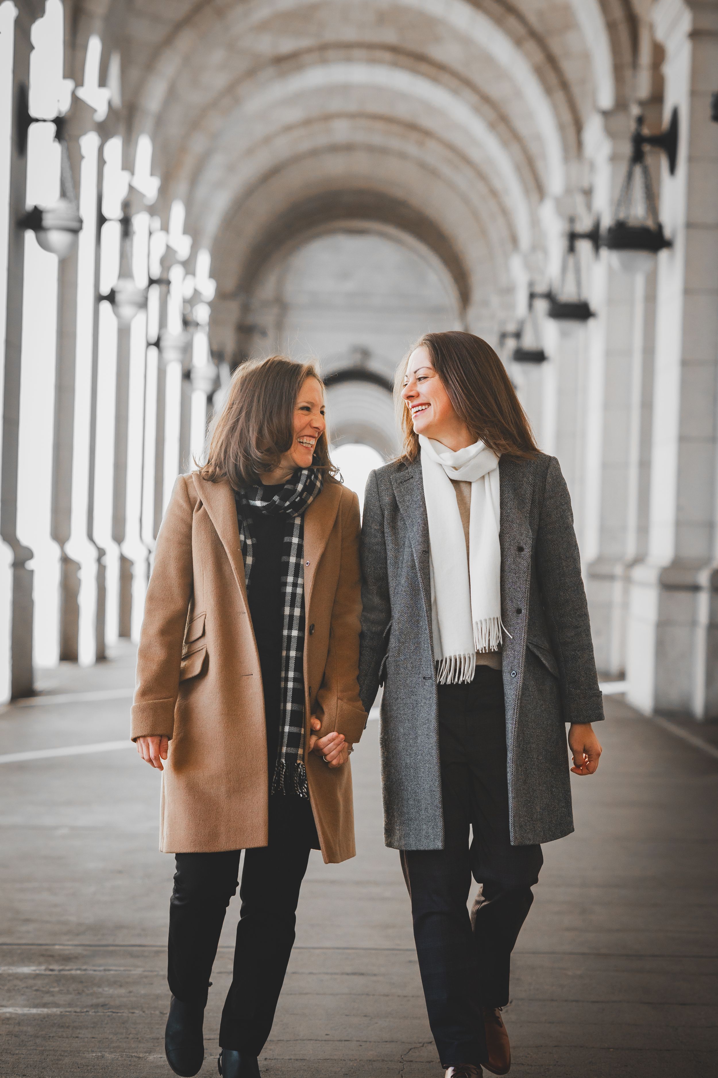 A couple walking and laughing together in the arched hallway of Union Station, one of the best winter spots for proposals in DC