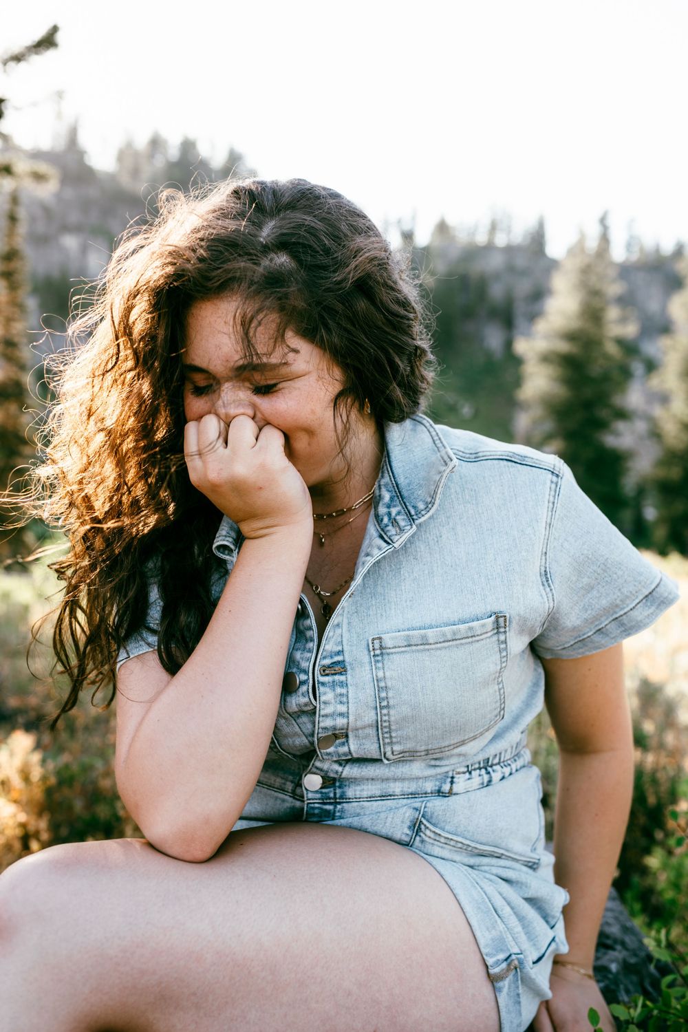 A couple shares intimate moments in a series of candid outdoor photos wearing denim against a natural backdrop.