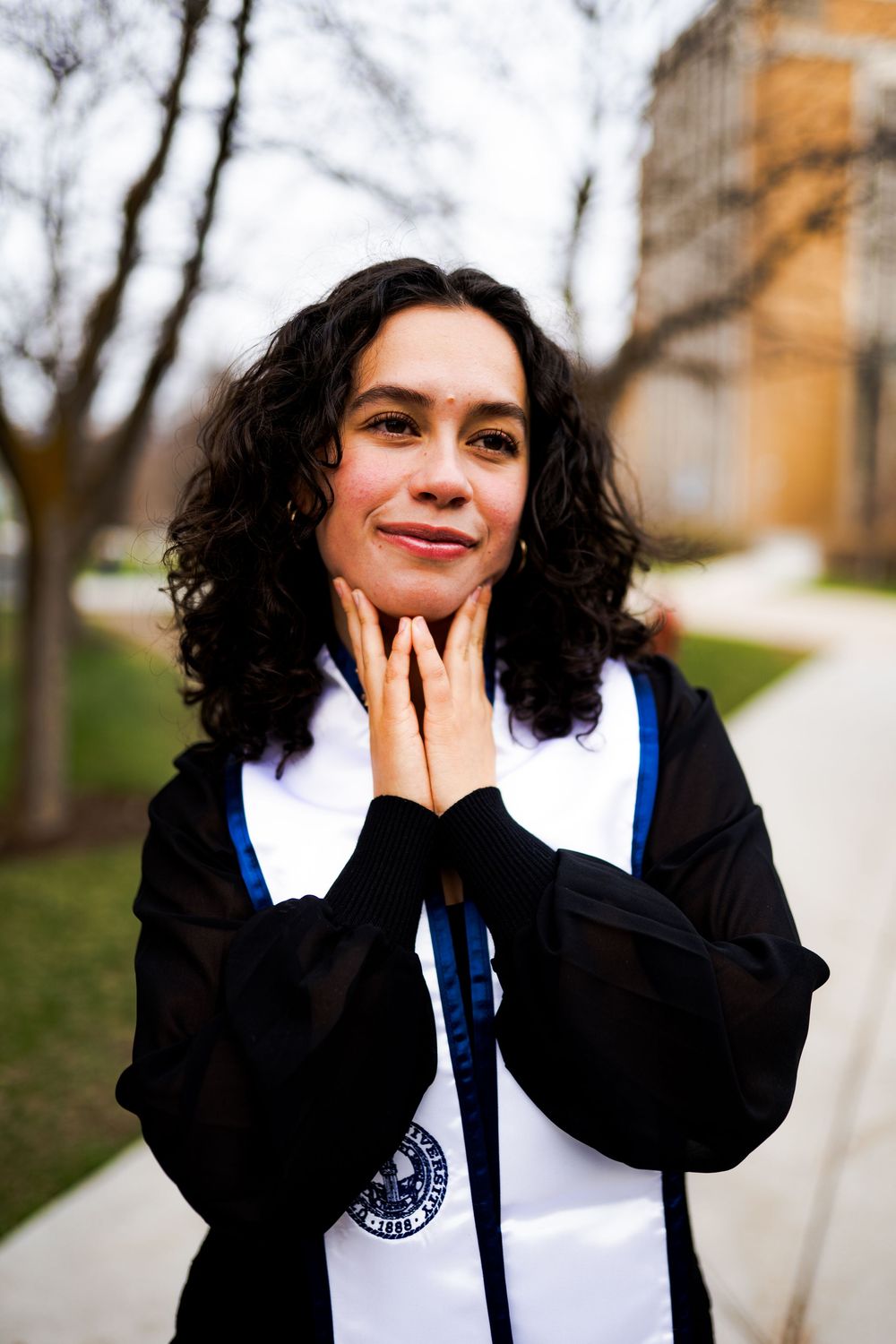 A person in graduation attire smiles joyfully while holding their face in a series of candid outdoor photos.