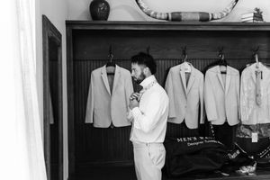 Black and white photo showing a row of white lab coats hanging on hooks in what appears to be a medical facility.