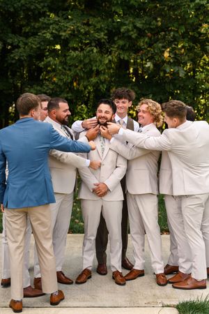Groomsmen in light colored suits and brown shoes pose together in a fun domino-style falling photo sequence.