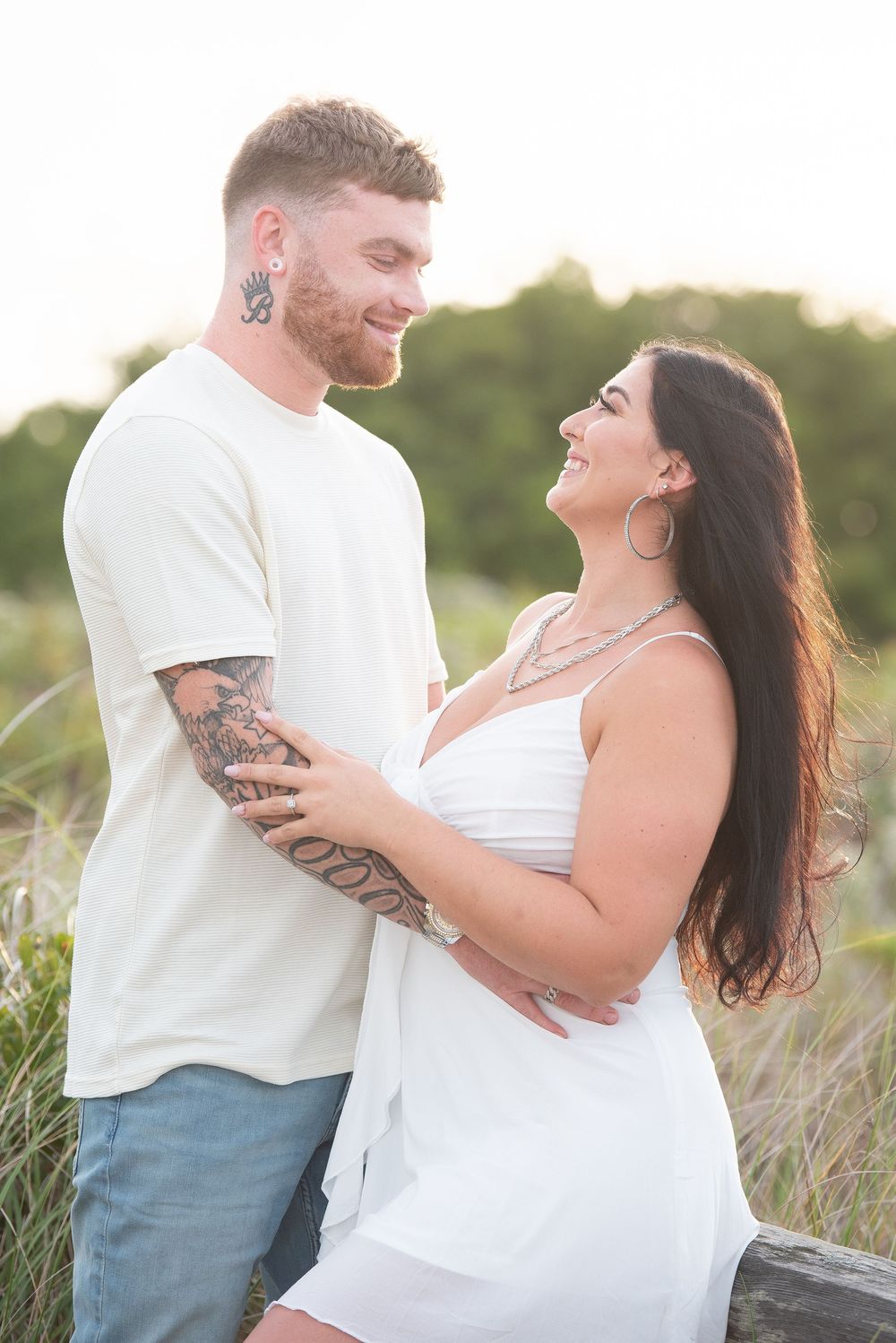Couple laughing together on beach path during golden hour.