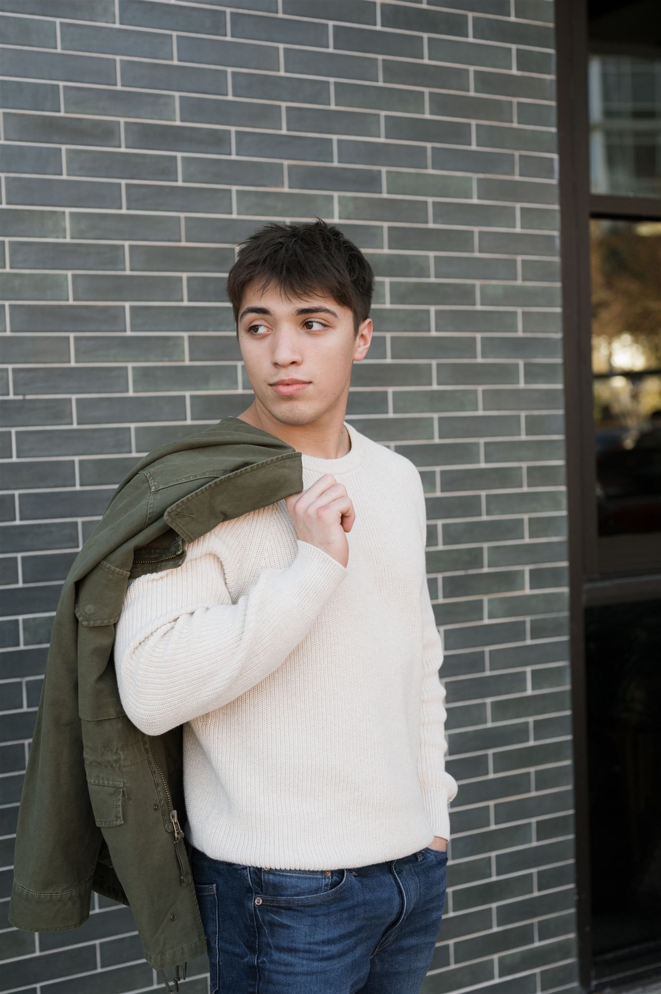 Three connected photos showing someone in a white sweater and jeans posing against a gray brick wall.