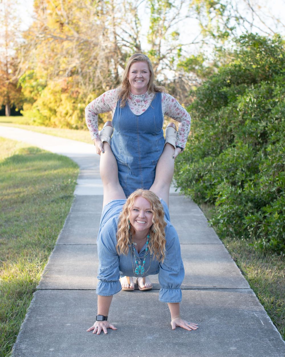 A person in denim performs playful poses on a concrete walkway with natural scenery in the background.