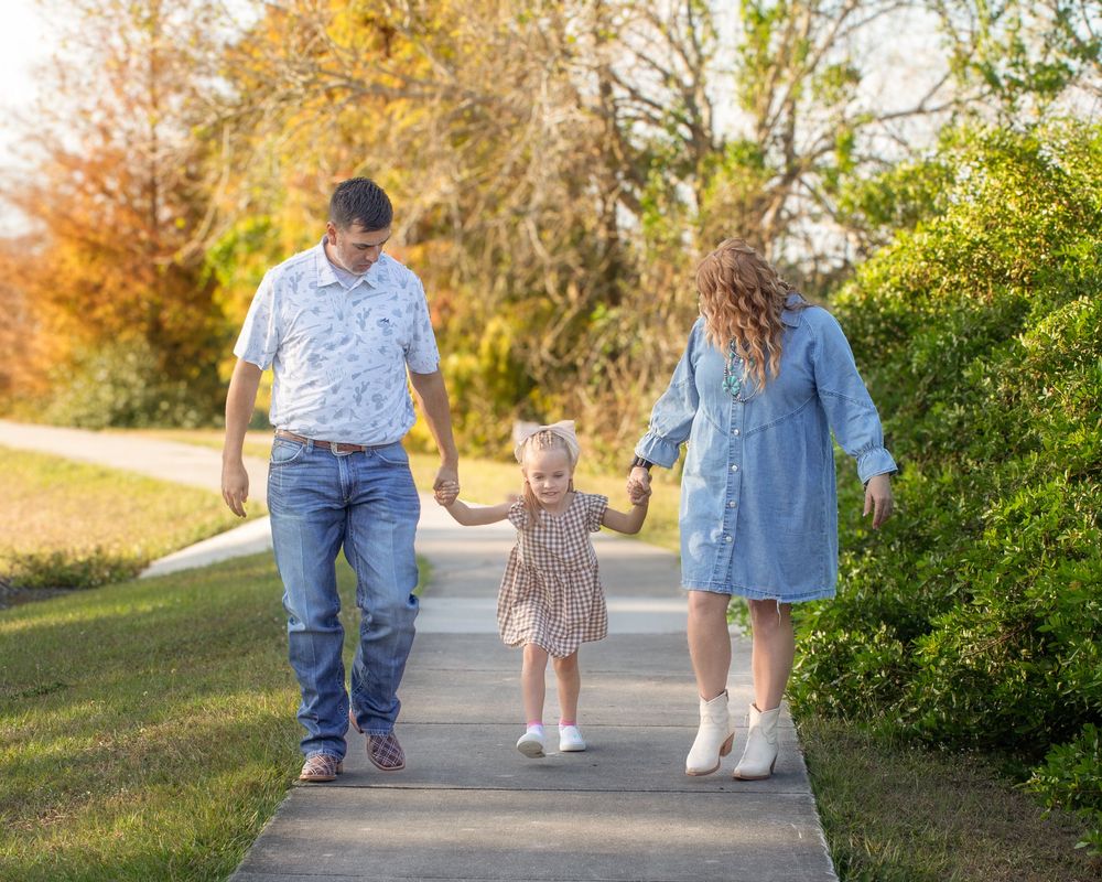 Family walking together on a path during golden autumn afternoon with fall foliage in background.