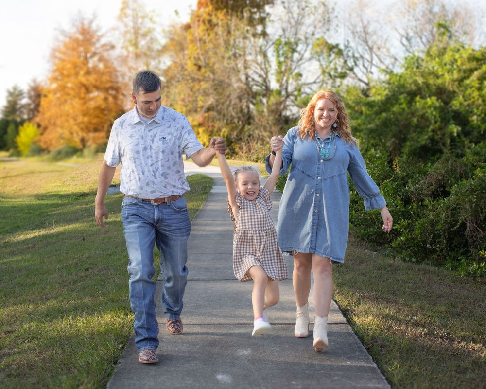 A family walking together on a paved path through a park during golden hour in autumn.