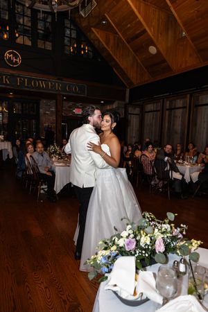 Wedding couple dances together in a rustic wooden reception venue with guests looking on. New Jersey wedding photographer