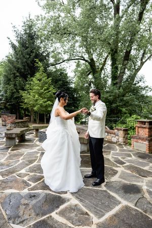 Wedding couple twirling and dancing together on an outdoor stone terrace with trees in the background. Sussex County wedding photographer
