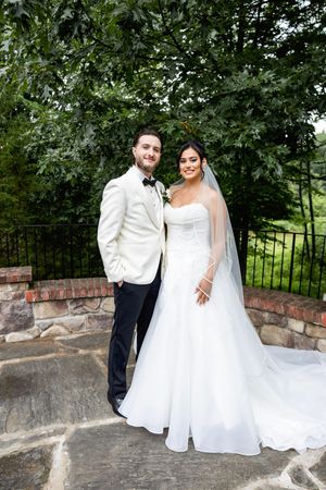 A romantic wedding couple poses together against a stone wall - Sussex County wedding photographer