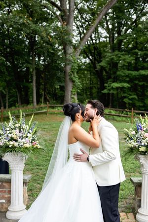 Newlyweds share an intimate moment in a garden setting surrounded by white floral arrangements. New Jersey wedding photographer