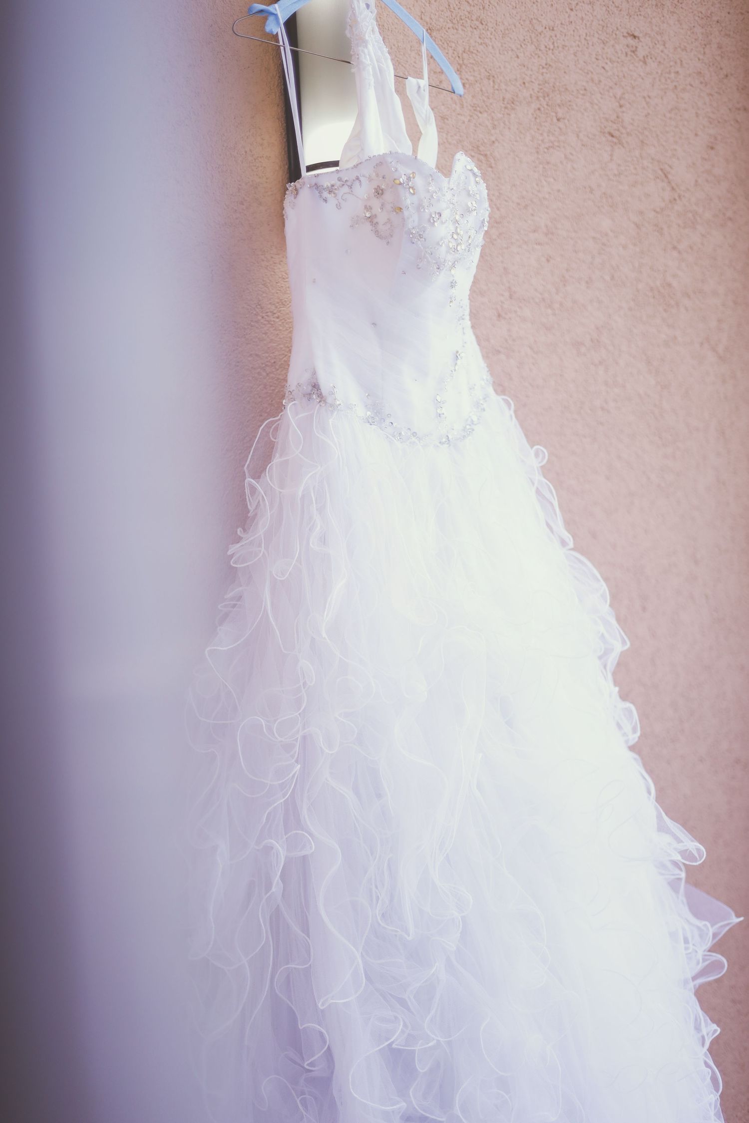 Close-up details of a white ruffled wedding dress with intricate layers of tulle fabric and delicate embellishments.