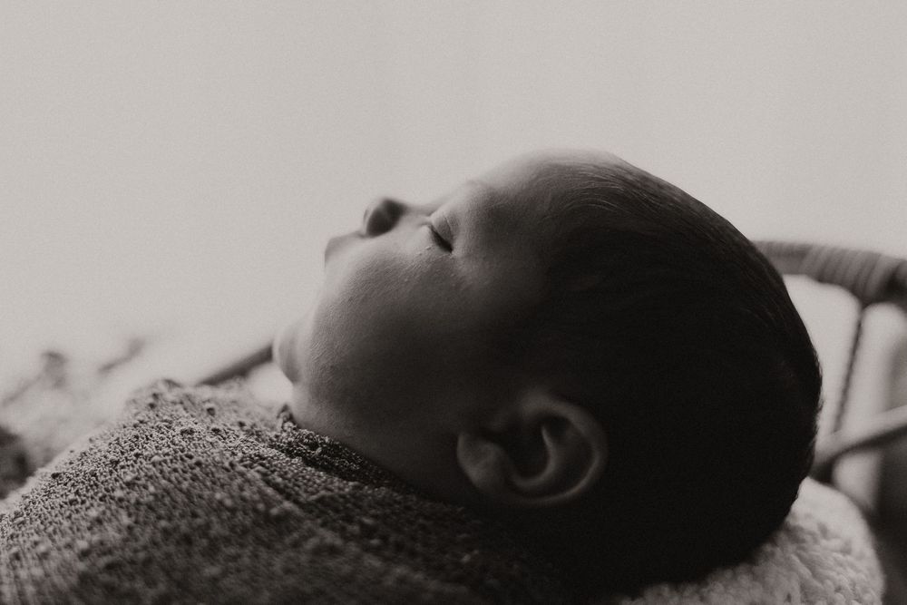 A series of black and white photographs showing a sleeping baby from different angles and perspectives.