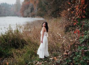 Ethereal autumn portrait in a white dress against fall foliage near a misty lake.