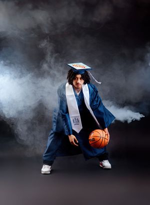 Creative graduation photos with smoke effects showing a graduate posing with a basketball in navy blue regalia.