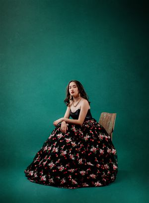 A floral black dress flows gracefully against a deep teal backdrop in a series of artistic fashion portraits.