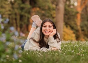 Someone lying in a grassy meadow with white wildflowers during golden hour in autumn.