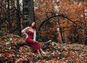 Artistic fall photoshoot captured in a wooded area with warm autumn colors.