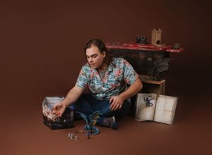Studio portrait featuring fantasy figurines and gaming accessories against brown backdrop.