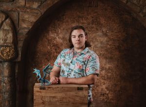 Themed portrait with medieval architecture and fantasy elements including a small dragon figure.