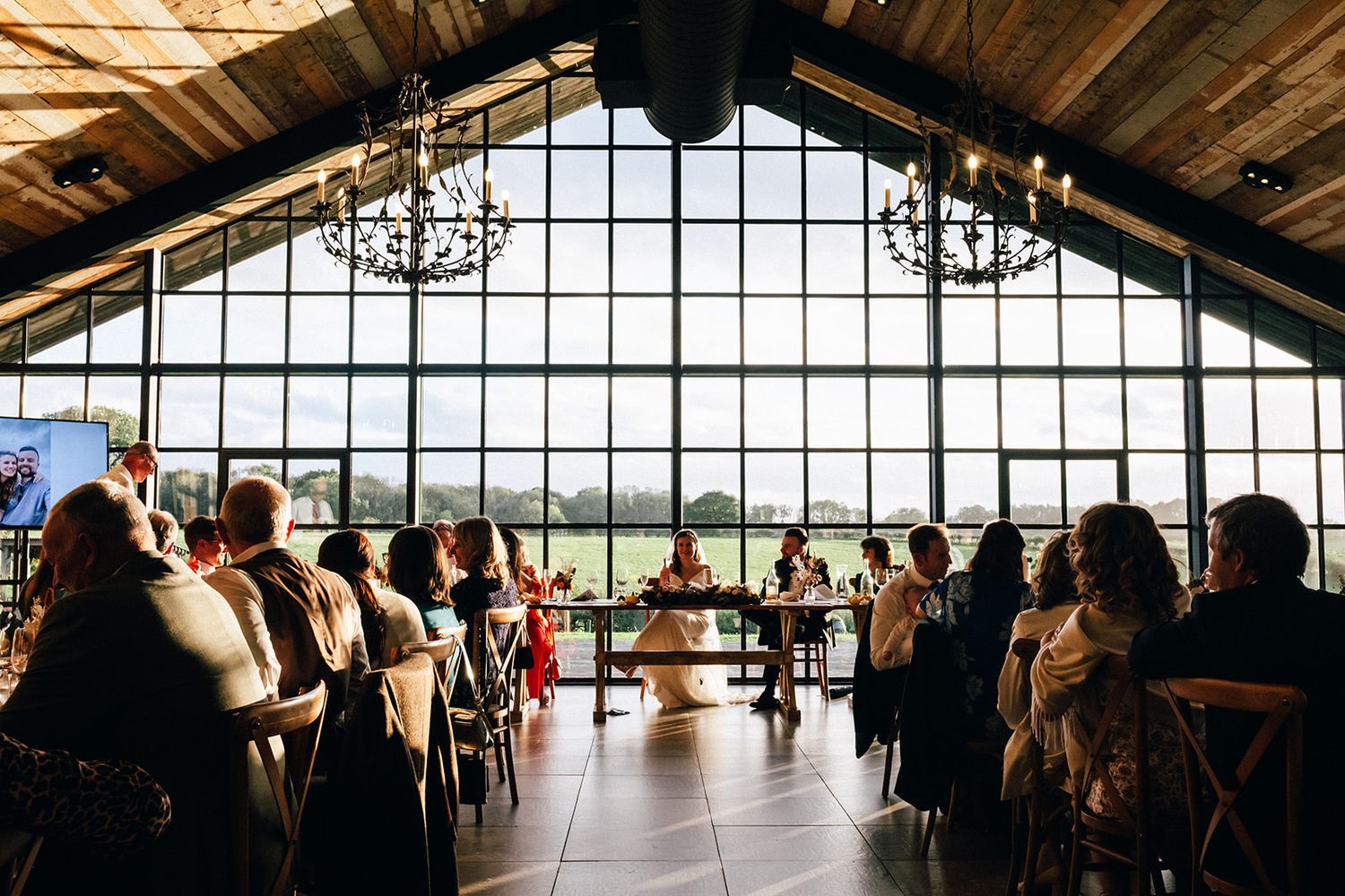 The Main Barn - A panoramic sequence of a modern restaurant interior with wooden beams and large windows overlooking a scenic view.